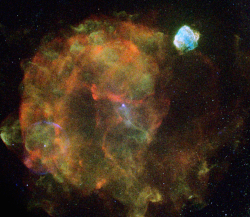 A false-color image of a large red supernova remnant next to a small blue supernova remnant, both looking like fireworks going off